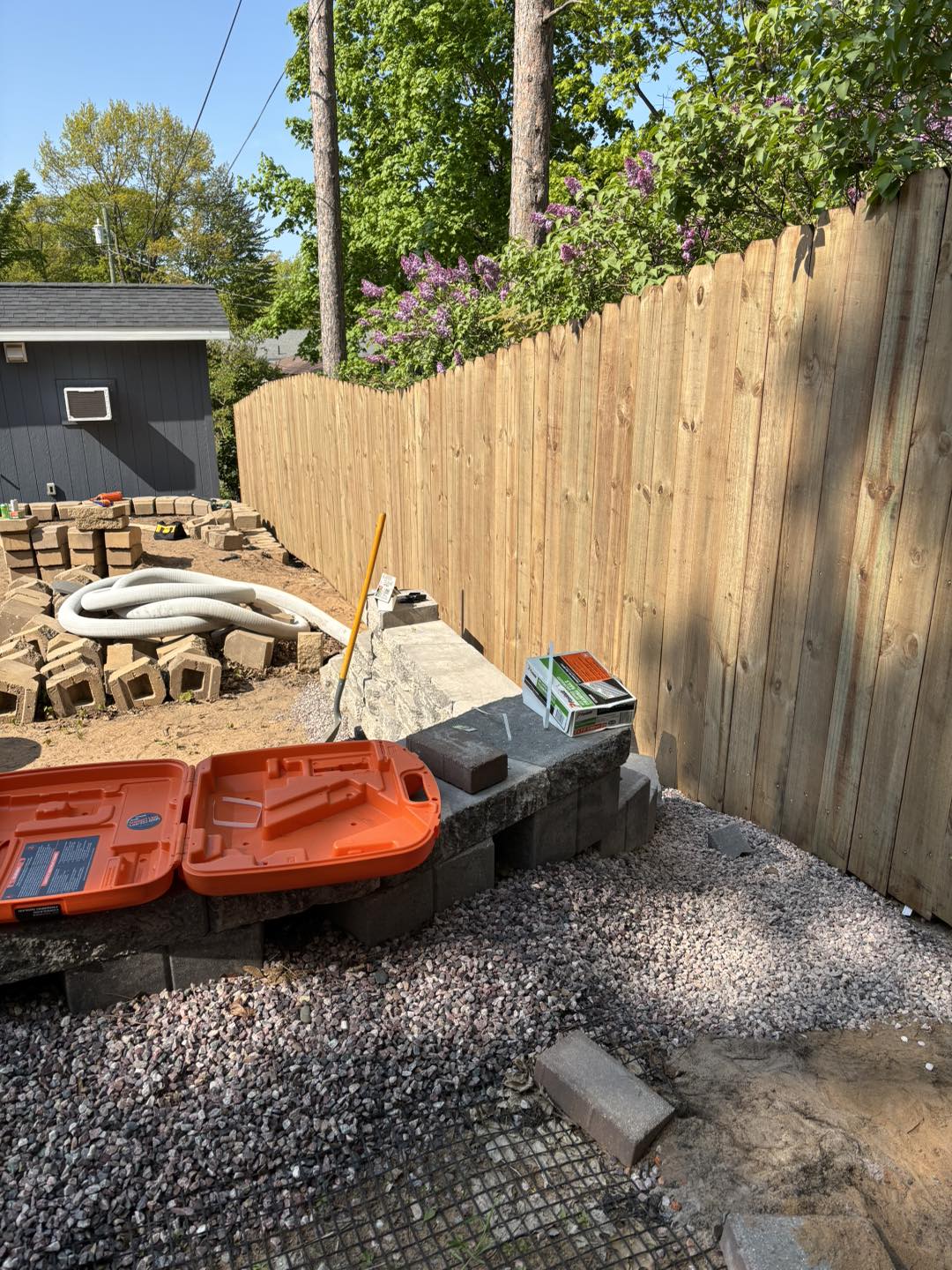 New wooden privacy fence being built on a stone wall.