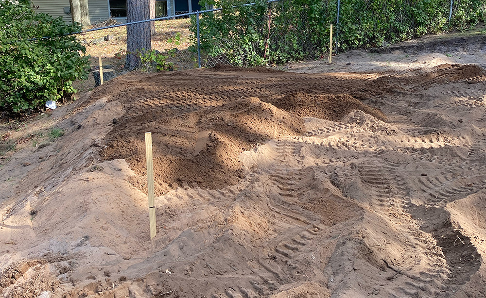 Piles of dirt and machine tracks on a graded house lot.