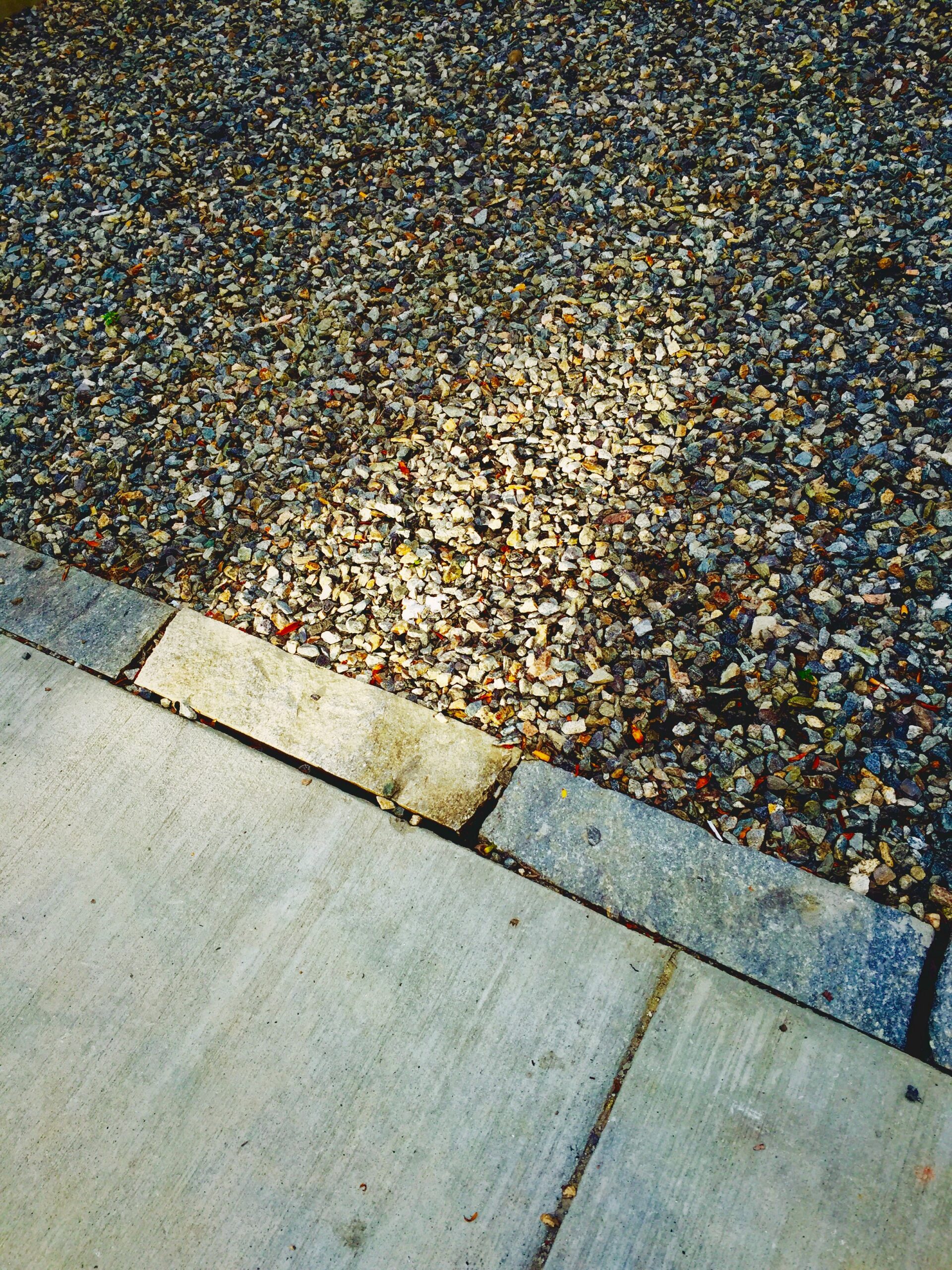 detail-shot-ground-as-background Concrete pad meeting a textured gravel surface at a border.